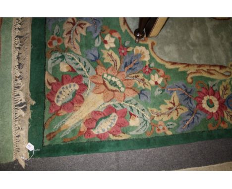 A 20th century Chinese wool carpet, woven with a bold central floral reserve with a conforming guard on a mid green ground, 2