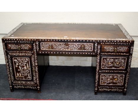 A late 19th/early 20th century Chinese hardwood, richly mother of pearl inlaid twin pedestal writing desk, the rectangular to