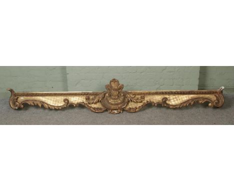 A very large gilt wood and plaster pelmet, worked with central floral crest surrounded by carved floral and swirled detailing