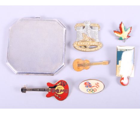 A silver powder compact with engine turned decoration, a silver and enamelled maple leaf badge, two Olympic badges, two Hard 