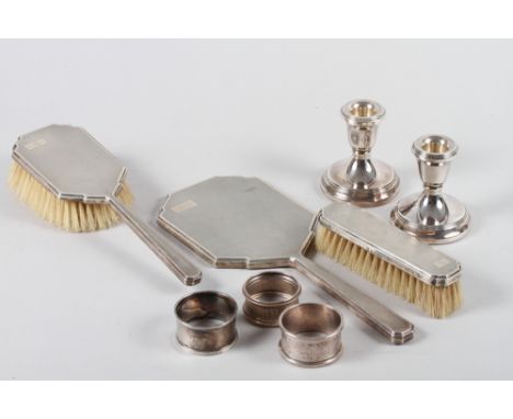 A silver three-piece dressing table set with engine turned decoration, a pair of filled silver candlesticks and three silver 