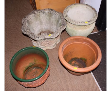 A stone planter with floral decoration, a similar planter and two terracotta planters, one with green glazed rim