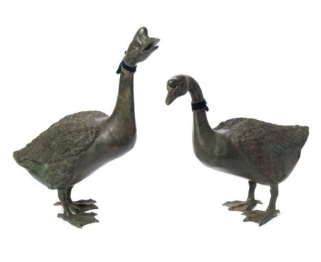 A pair of life-sized bronze geese: both standing, one looking upward, 53cm and 67cm. high.