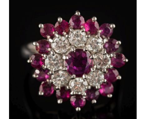 A ruby and diamond circular cluster ring: with single circular ruby within a surround of brilliant-cut diamonds and smaller c