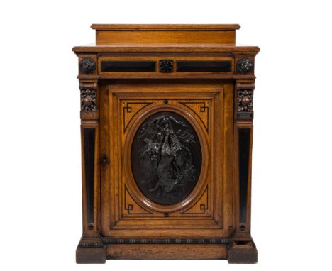 A Victorian oak, ebonised and bronzed mounted upright cellarette cupboard: with a ledge back, the frieze with raised bevelled