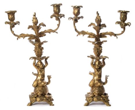 A pair of 19th century ormolu candlesticks: the twin foliate branches with urn shaped nozzles, each on a foliate stem support