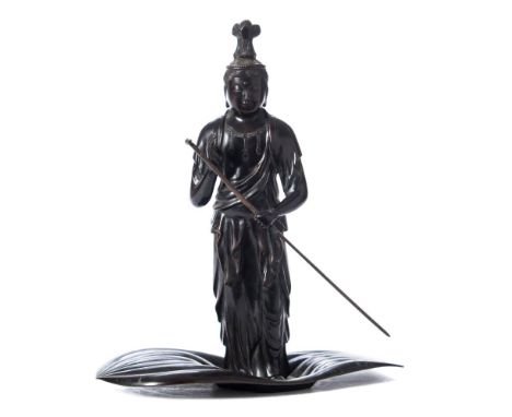 A Japanese bronze figure of Kwannon: standing in a lotus leaf boat with a paddle in her hand, unsigned, 31cm. high.