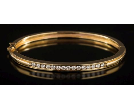 A diamond mounted hinged bangle: channel-set with a line of circular brilliant-cut diamonds estimated to weigh a total of 0.7