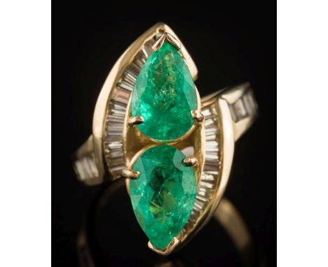 An emerald and diamond mounted cluster crossover ring: with two pear-shaped emeralds, each approximately 10mm long x 6mm wide