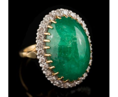 A cabochon emerald and diamond oval cluster ring: the oval cabochon emerald approximately 22mm long x 16.4mm wide x 9.5mm dee