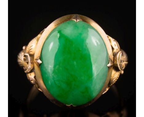 A jade mounted, single-stone ring: the oval jade 15.7mm long x 12.5mm wide, in four claw setting and between pierced foliate 