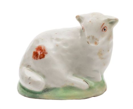 A Lowestoft model of a reclining ewe: of small size, with iron red markings, on green mound base, circa 1780-85, 4.5 cm. long