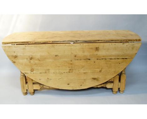 A large heavy pine dropleaf dining table, with circular top on turned gate legs and turned stretchers, 183cm x 182cm