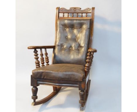 A Victorian rocking chair, carved scroll cresting rail and button upholstered back in leather, turned spindle supports to the