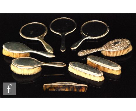 Three hallmarked silver backed hand mirrors to include an inlaid tortoiseshell example with five silver backed brushes and a 
