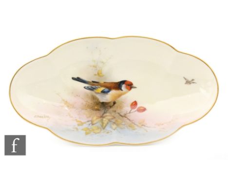 A Royal Worcester oval shaped scalloped edge dish decorated by E. Barker with a hand painted goldfinch perched on a branch, a