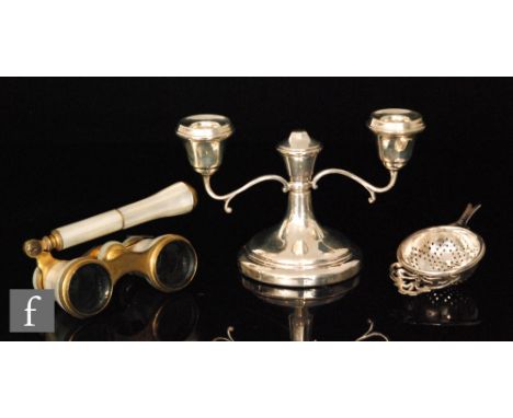A hallmarked silver twin light squat candelabra, height 10cm, Birmingham 1970, with a silver tea strainer and a pair of mothe
