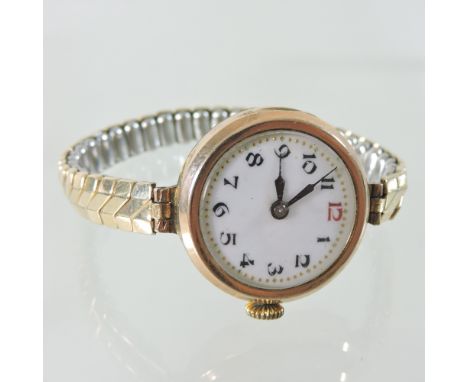 An early 20th century 9 carat gold cased ladies wristwatch, with a white enamel dial, on an expanding strap
