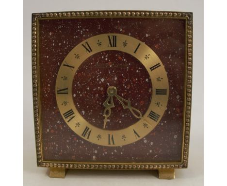 A Jaeger-Le Coultre gilt metal mantel clock, of square form with paint flicks to a burgundy&nbsp;ground and gilt chapter ring