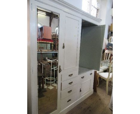 A PAINTED THREE DOOR CUPBOARD, HAVING MIRROR DOOR HANGING SPACE TO THE LEFT, A CENTRAL SHELF UNIT ABOVE FOUR DRAWERS, AND MAR