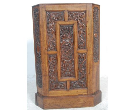 A Victorian 19th century carved oak corner stick stand. Raised on a plinth base with carved fielded panel centre with canted 