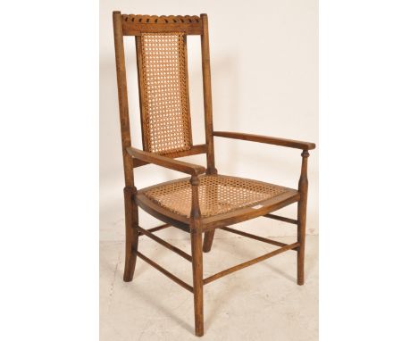 An early 20th century circa 1920’s oak and cane elbow bedroom chair / armchair. The chair having pierced and carved top rail,