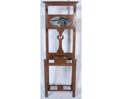 A vintage mid 20th century oak hall stand having a flared top over two metal hooks with a central mirrors over a pierced back