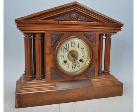 A late 19th century Victorian early 20th century walnut mantel clock of architectural form having a white enamel clock face w