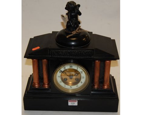 A late Victorian black slate mantel clock of architectural form having an enamel dial with Arabic numerals and eight day move