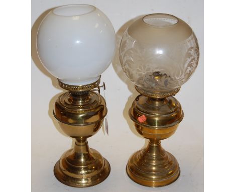 An early 20th century brass oil lamp having an etched globular glass shade on pedestal base together with one other similar (