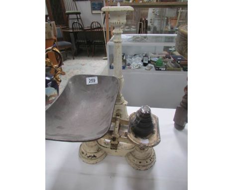 A set of kitchen scales with weights and a metal candlestick.