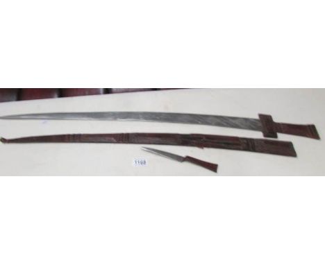 An early 20th century sword with engraved blade and in decorative scabbard with skinning knife.