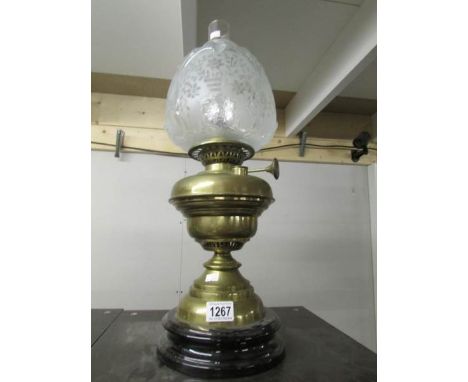 A brass oil lamp with pot base, complete with shade and chimney.