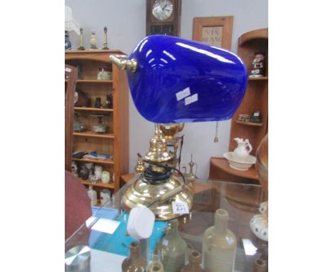 A large bankers lamp with glass shade.