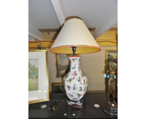 A pottery table lamp decorated with butterflies and complete with shade.