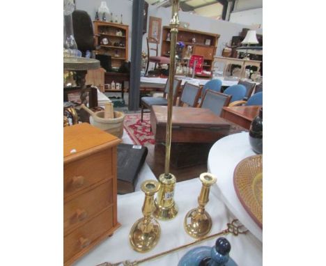 A brass poker in stand, a pair of brass candlesticks and a toasting fork.