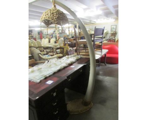 An ornate standard lamp with elephant tusk style column, gilded base and gilded shade.