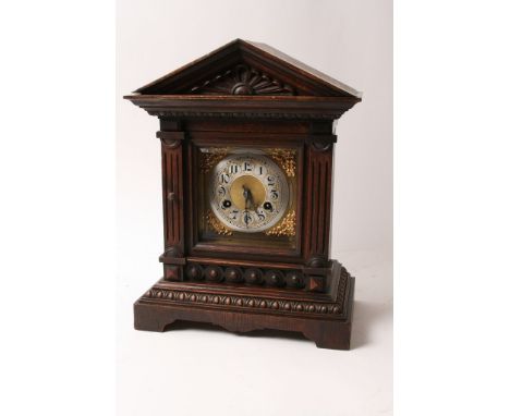 An oak cased mantle clock having square brass dial and silvered chapter ring with Arabic numerals