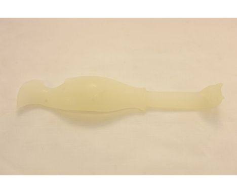 A Chinese light green jade belt buckle in the form of a stylized fish
