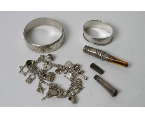 A small collection of silver comprising a charm bracelet, bangle, napkin ring and cigarette holder