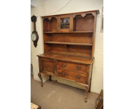 An oak arts and crafts style dresser with single lead light door, open shelf's, cupboard and drawers under on cabriole legs