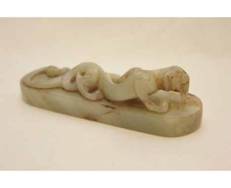 A Chinese jade paperweight in the form of a stylized dragon on an oval base