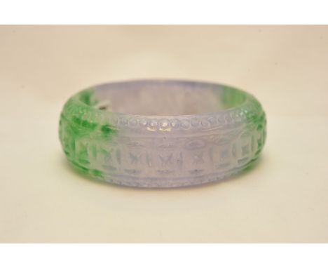 A 20th century two tone colour jade bangle with carved decoration