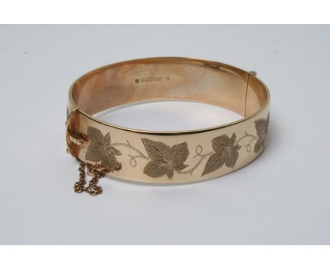 A 9ct gold bangle engraved with maple leafs