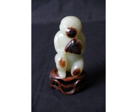 A carved jade monkey on wooden stand, approximately  8cm high