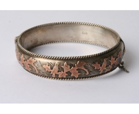 A silver and gold mounted bangle with leaf design