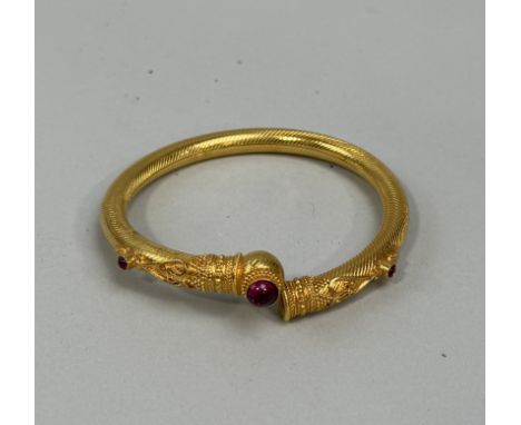 AN INDIAN GOLD TONE BANGLE WITH RED STONES 