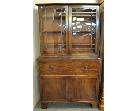 Early 19th Century mahogany two stage secretaire bookcase, the moulded cornice above two glazed doors, the interior revealing