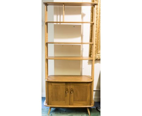 An Ercol light elm and beech shelf unit, the shelves supported on tapered urprights over a cupboard base