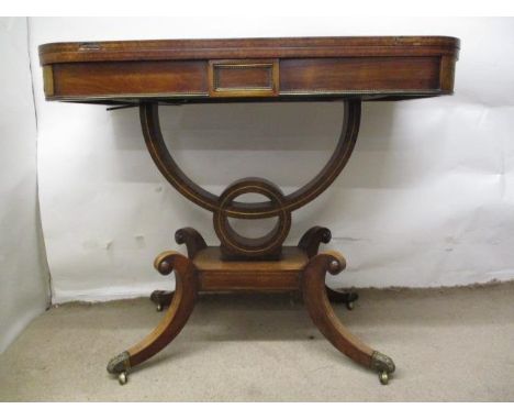 A Regency satinwood and brass inlaid rosewood card table, with a rotating, foldover top, over a breakfront frieze with brass 